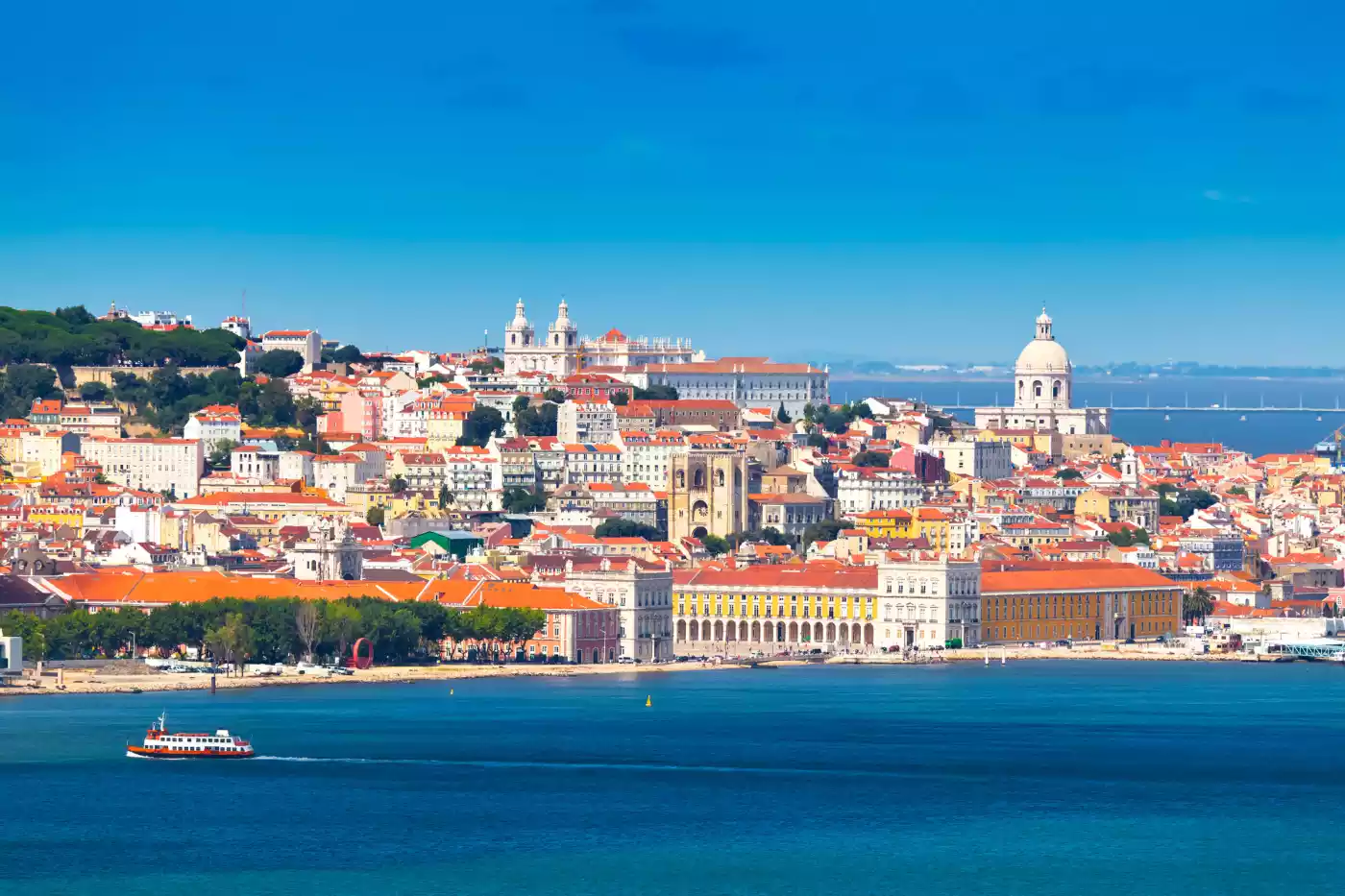 Lisbon’s waterfront and old town across the Tagus, with a ferry crossing